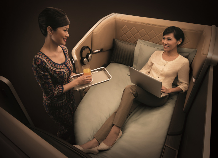 A woman relaxing and talking with the attendant on her international flight.