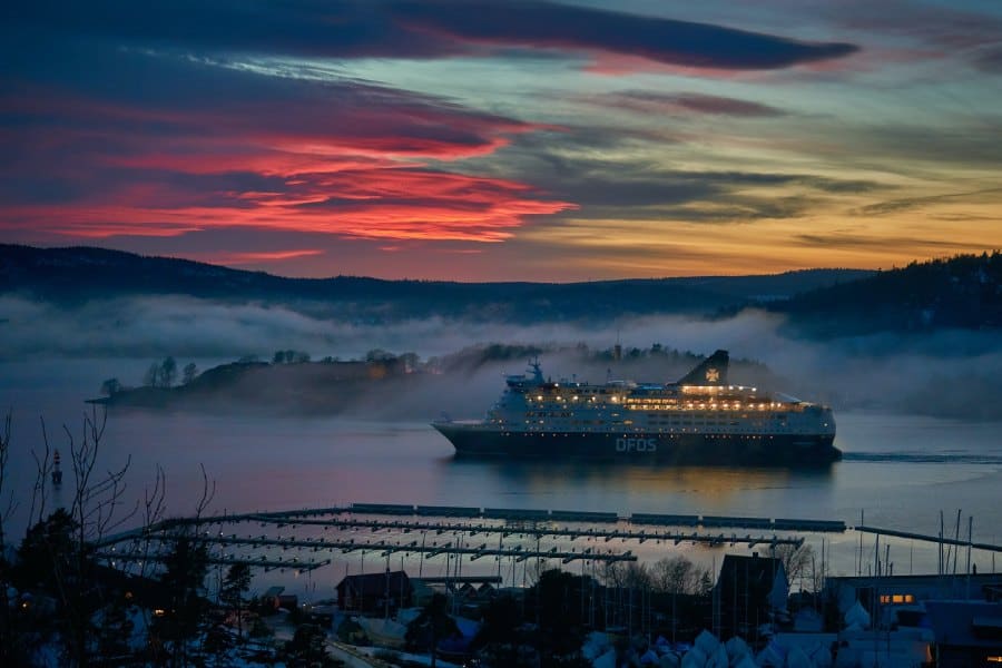 colorful pink and orange sunset behind a ship at sea during winter