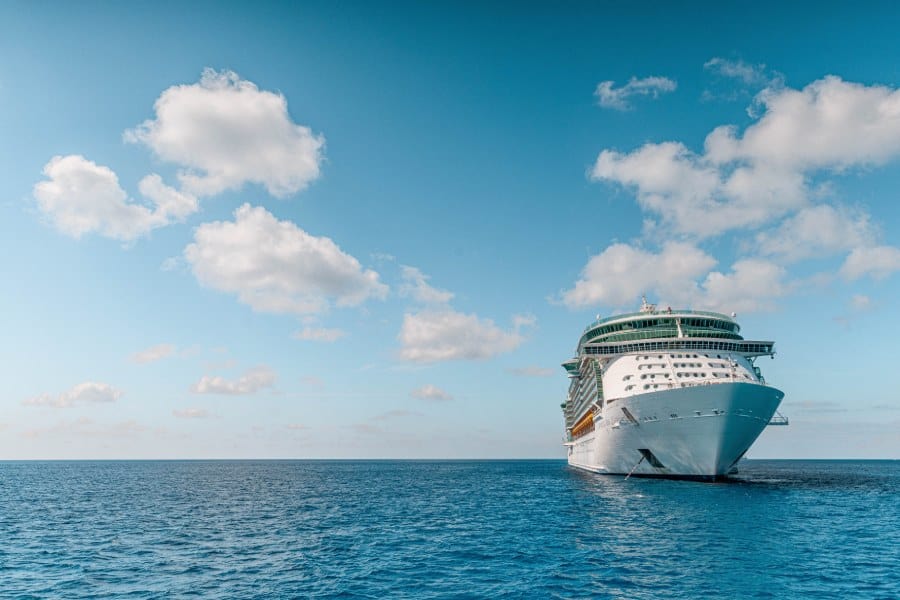 cruise ship on the sea with puffy clouds behind it